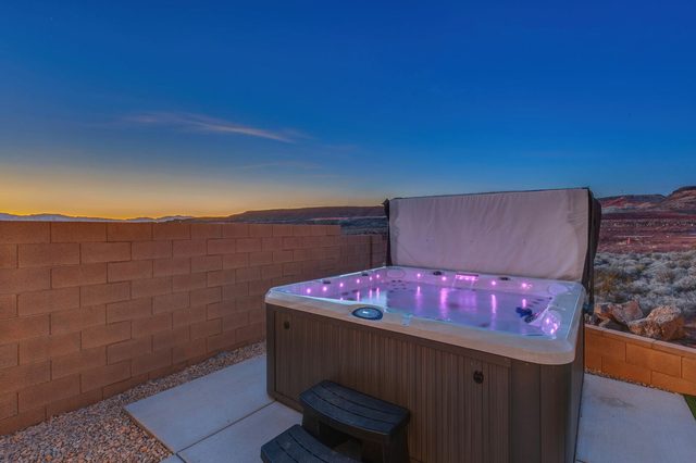 Private hot tub with purple lights beside the backyard wall