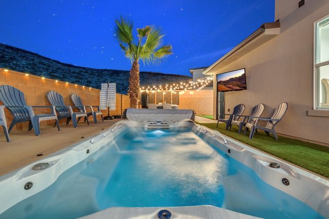 Private swim spa with Adirondack chairs and string lights at dusk