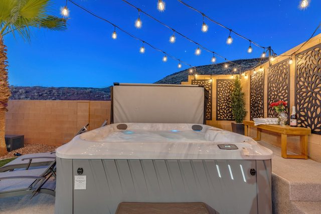 Private hot tub under string lights with decorative screens