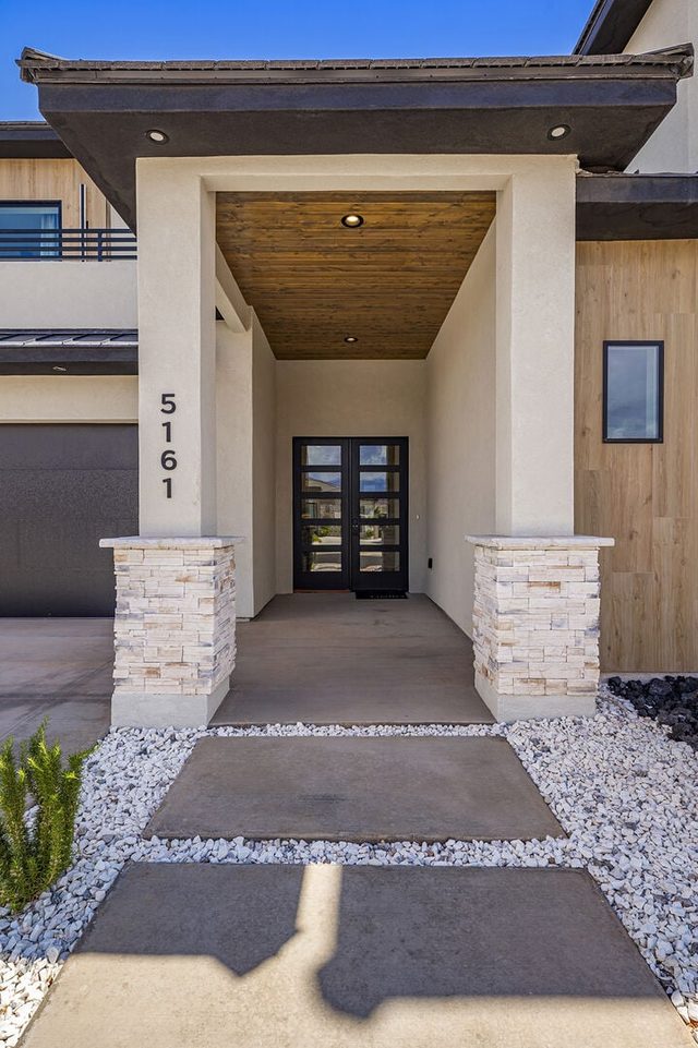 Covered front entry walkway with stone columns and glass doors