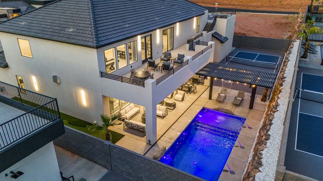 Aerial view of the lit private pool and covered patio at dusk