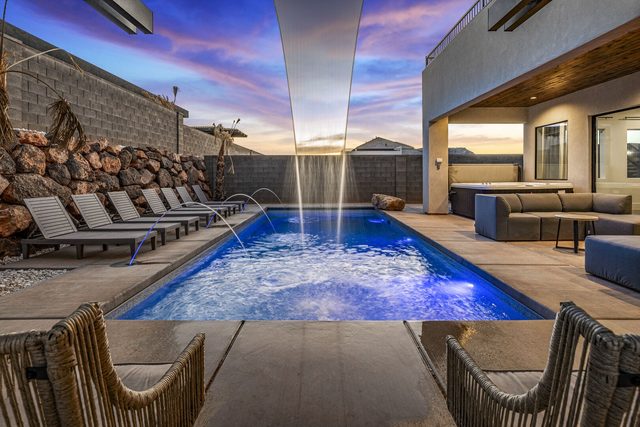 Private pool with waterfall feature and loungers at sunset