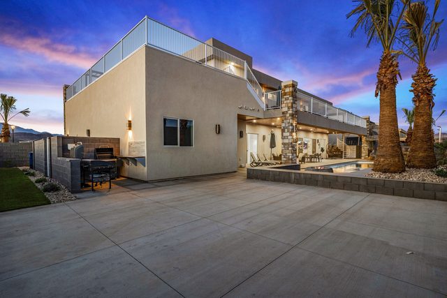 Side of the home with driveway and palm trees at dusk