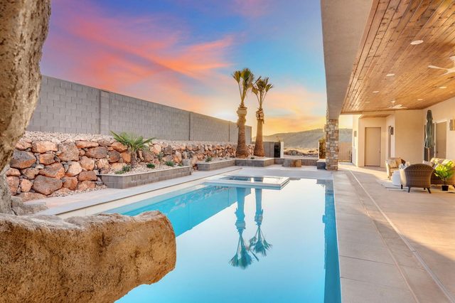 Private pool with rock feature and covered patio at sunset
