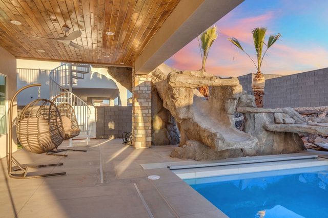 Pool slide rock feature and hanging egg chair on the patio