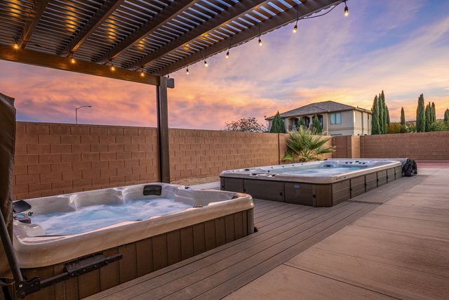 Private hot tub and swim spa under a lit pergola