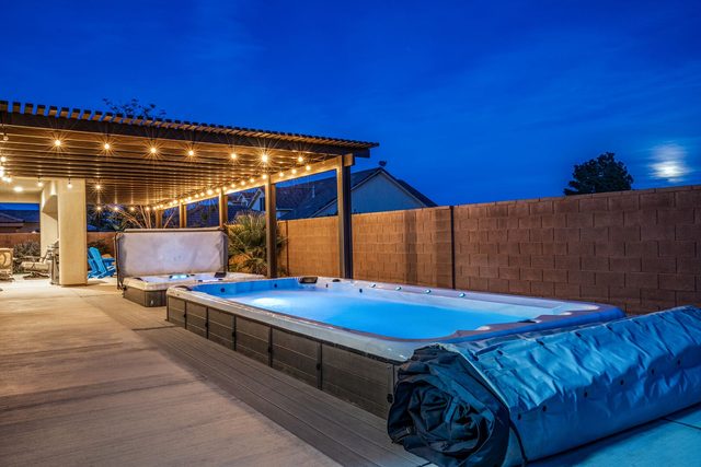 Swim spa and hot tub at night with string lights
