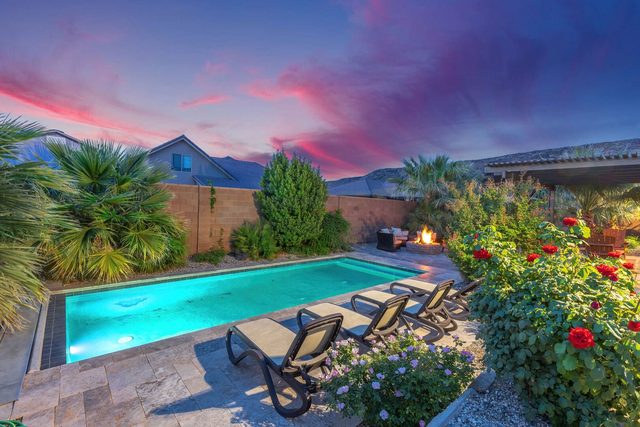 Private pool with lounge chairs, roses and palms at dusk