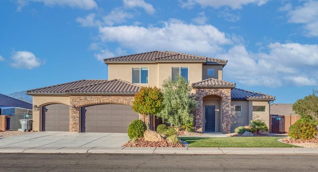 Front exterior of Sand Hollow 3370 with three-car garage and landscaping