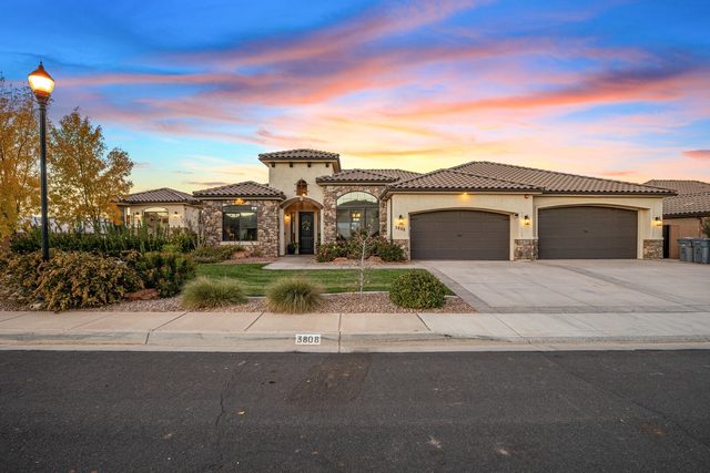 Front exterior of Sand Hollow 3808 with three-car garage at sunset