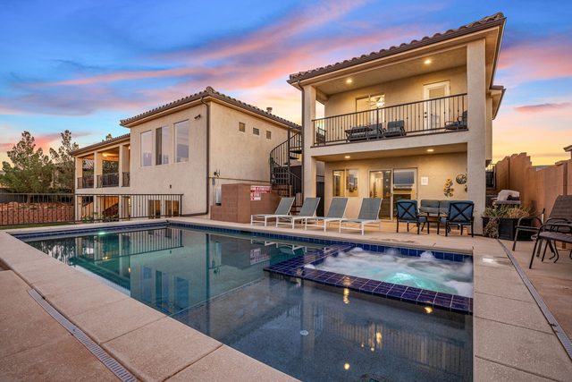 Private pool and spa with the lit home at dusk