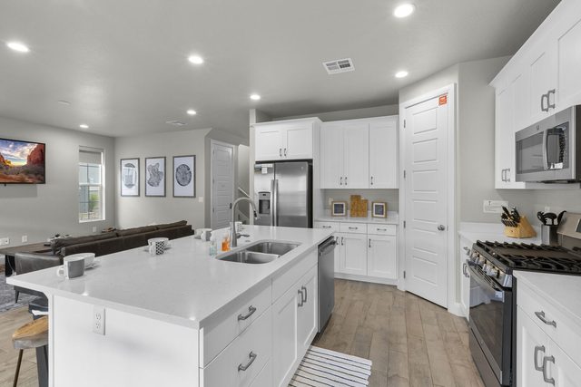White kitchen with island, stainless appliances and gas range in home 2311