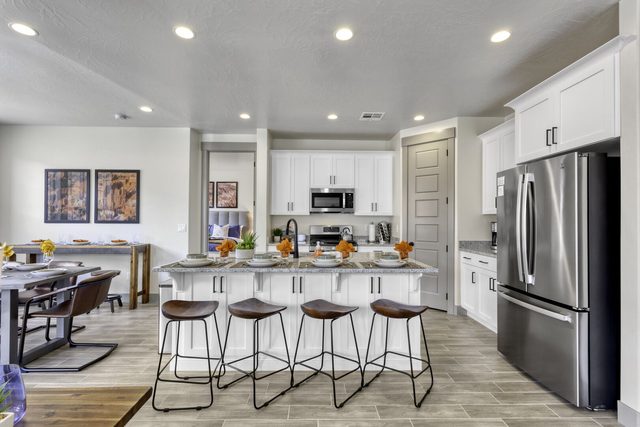 Kitchen island with four bar stools and stainless fridge in home 2323