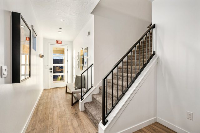 Front entry and staircase with wood floors and black railing