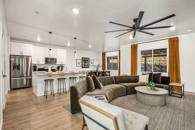 Open living room with curved sectional facing the white kitchen