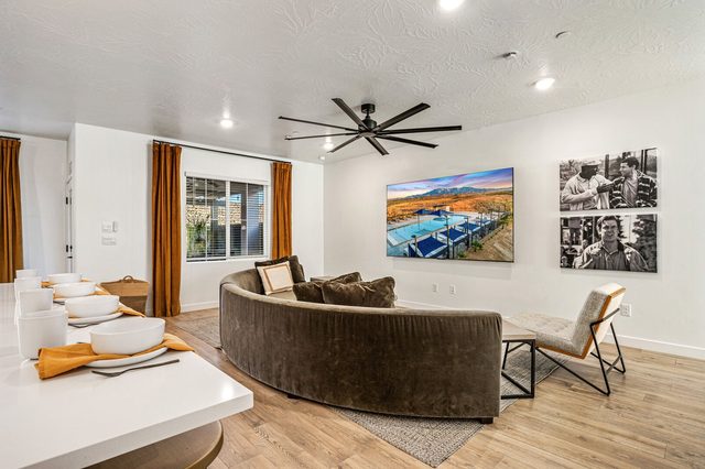 Curved sectional sofa beneath large wall TV and framed photos