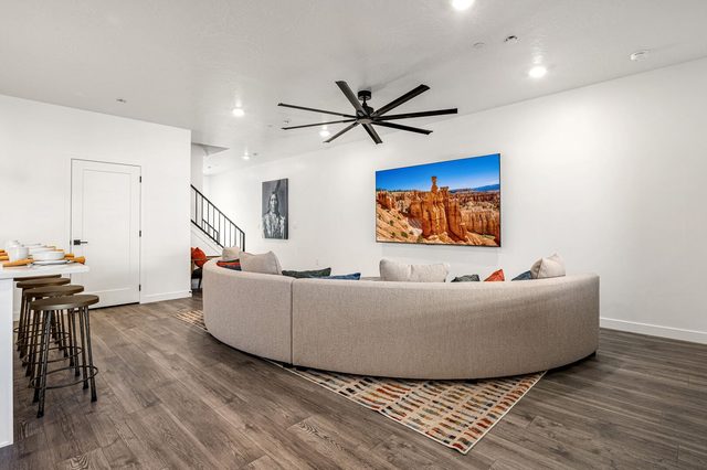 Living room sectional beside kitchen bar stools and stairs