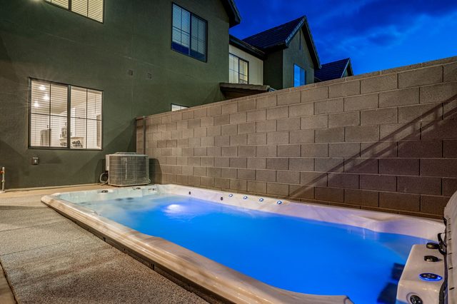 Swim spa glowing blue at dusk behind the townhome