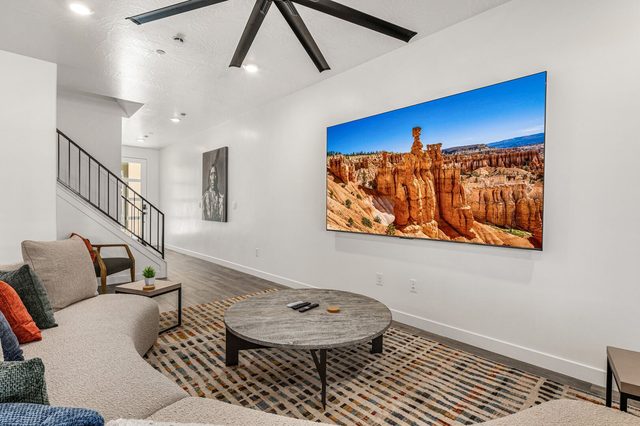 Living room seating with wall TV and staircase behind