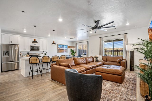 Open great room with leather sectional and white kitchen beyond