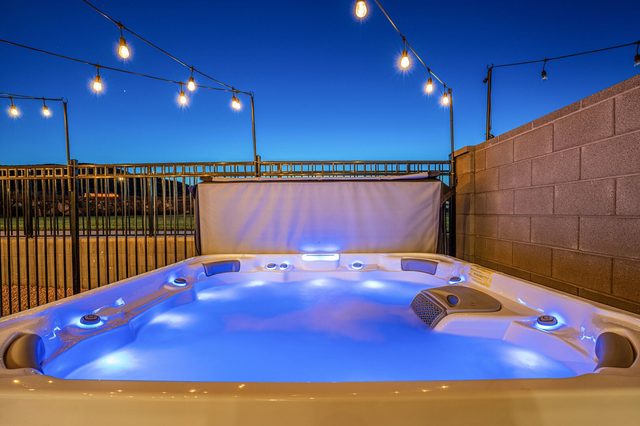 Private hot tub with blue lighting under string lights