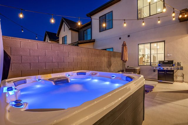 Lit private hot tub beside the backyard grill at dusk
