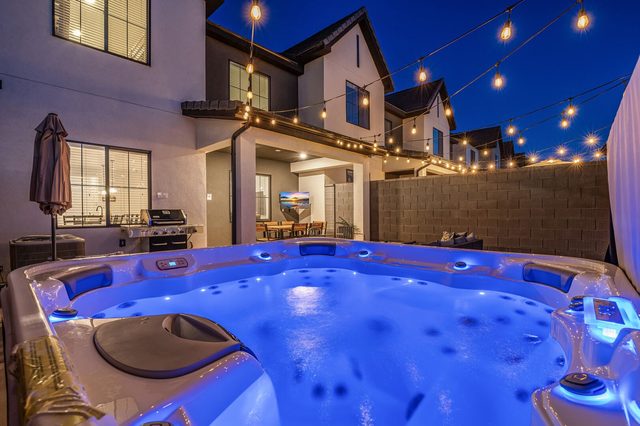 Private hot tub glowing at night beneath string lights