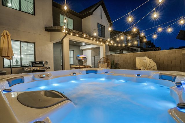 Illuminated private hot tub with grill and house behind