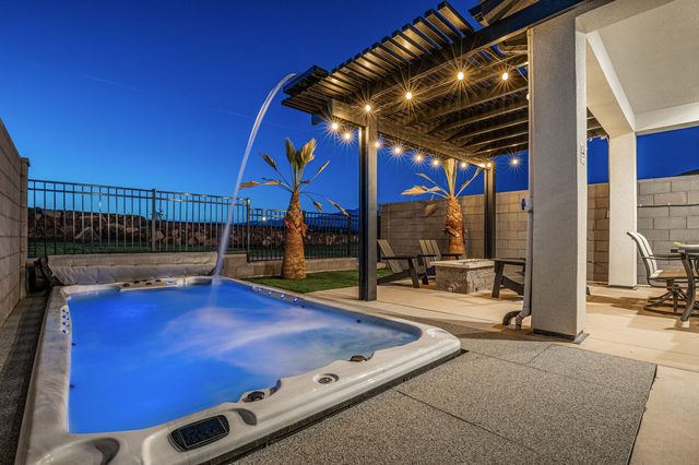 Illuminated private swim spa beside the pergola at dusk