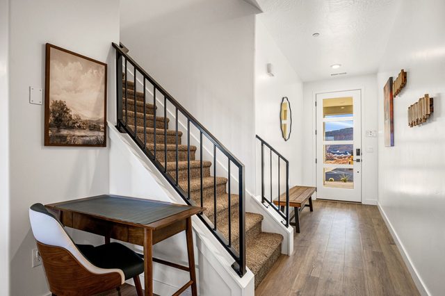 Entry hall with small desk and carpeted staircase to the upper floor