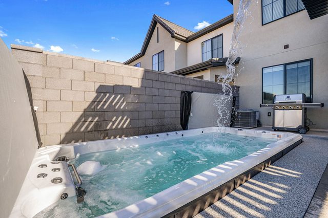 Swim spa next to the gas grill along the back of the home