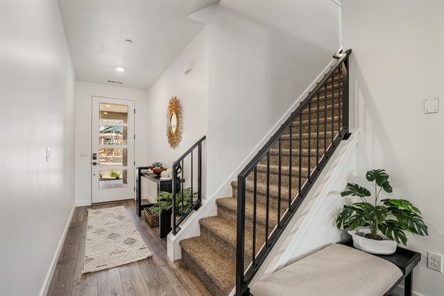 Entry hall and carpeted staircase with black metal railing