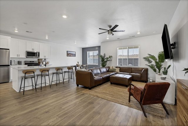 Open living room with leather sectional beside the kitchen island bar seating