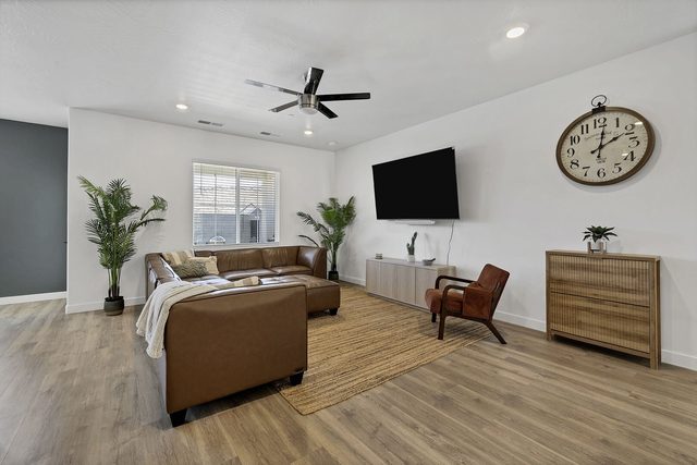 Living room with leather sectional, wall-mounted TV and ceiling fan