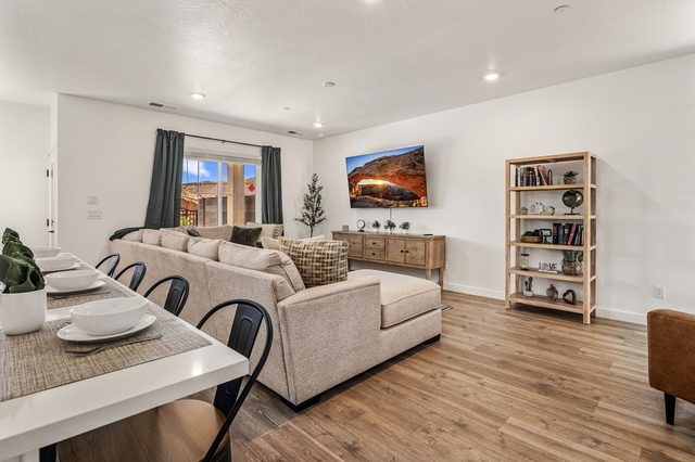Living room sectional and wall-mounted TV beside the dining table