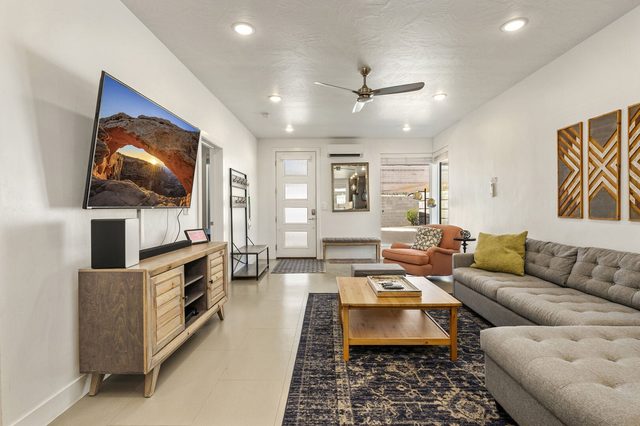 Living room with gray sectional, coffee table and wall-mounted TV at The Lofts 13