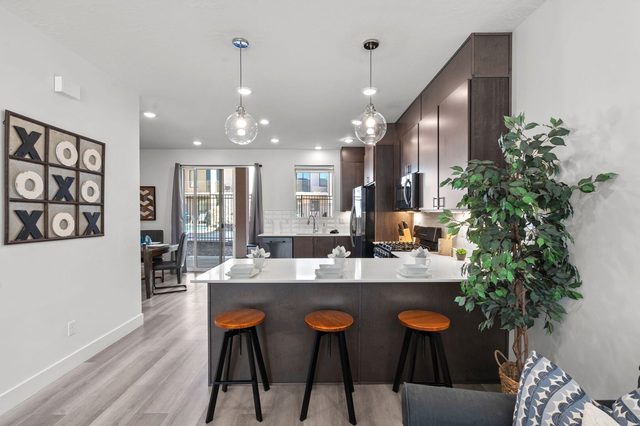 Kitchen bar with three stools and pendant lights at The Lofts 2