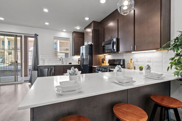 Quartz kitchen peninsula with bar stools and dark wood cabinets