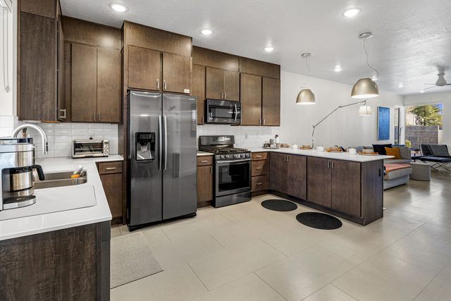 Kitchen with stainless refrigerator, gas range and dark cabinets