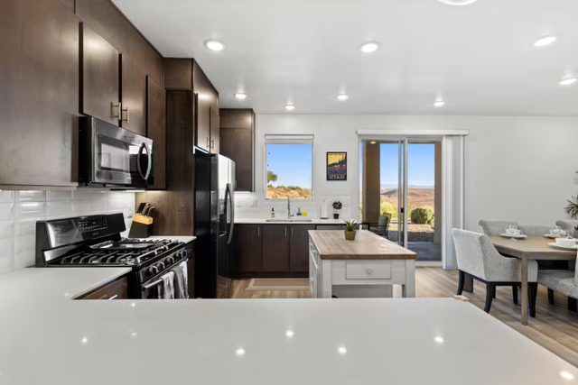 Kitchen with dark cabinets and butcher block island near dining