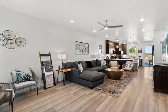 Open living room with sectional, ceiling fan and kitchen beyond