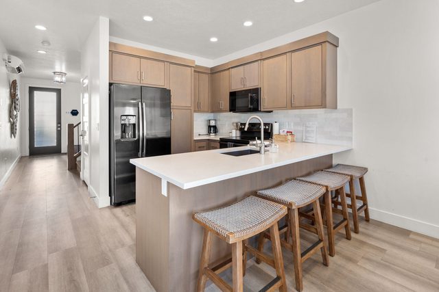 Kitchen peninsula with bar stools and black stainless fridge