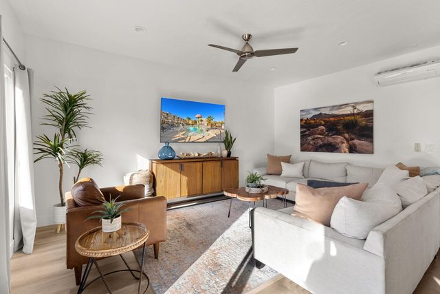 Living room with white sectional, leather armchair and wall TV at The Vues 12