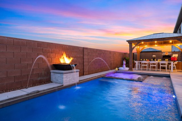 Private pool with water jets, fire bowl and gazebo behind it