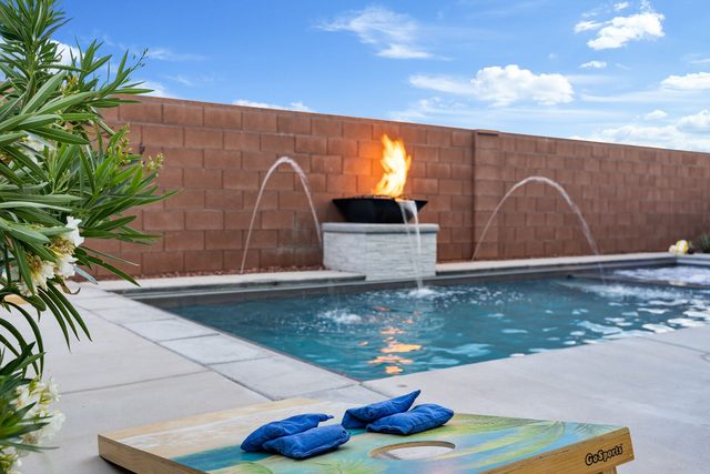 Private pool with fire bowl water feature and cornhole boards