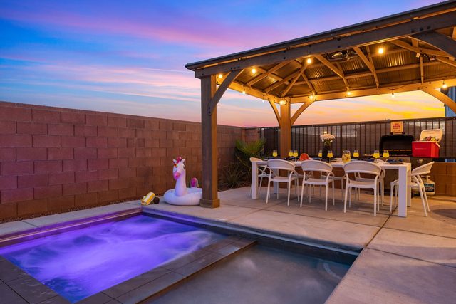 Lit private hot tub beside the gazebo dining area at dusk
