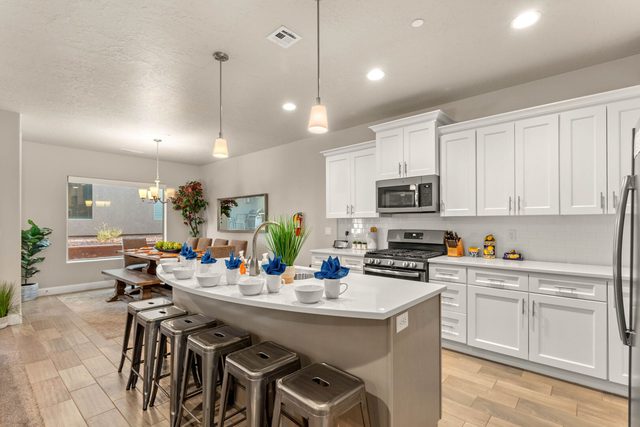 White kitchen with island bar seating and dining area beyond