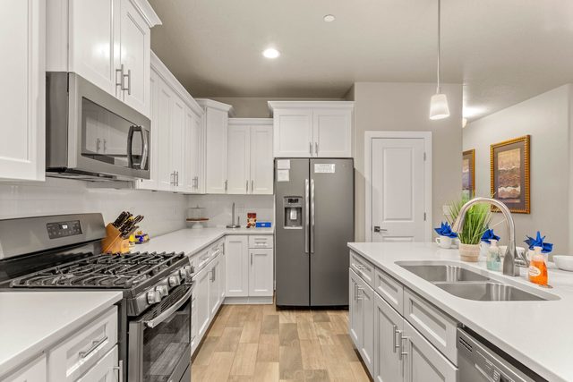 Kitchen with gas range, stainless refrigerator and white cabinets