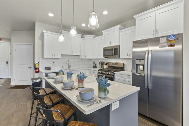 Kitchen island with bar stools and stainless steel refrigerator