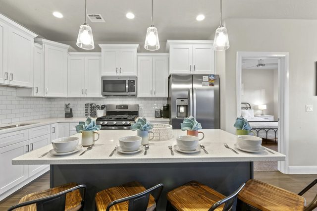 Kitchen island with five stools, gas range and white cabinets